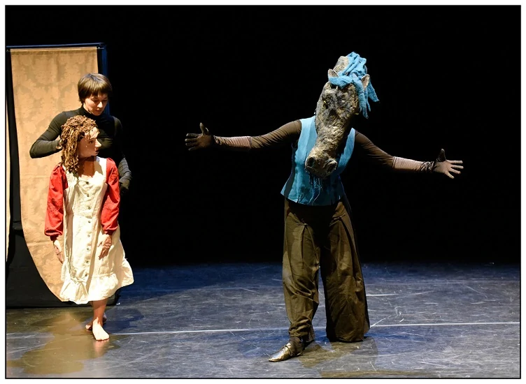 photo de spectacle une jeune femme manipule une marionnette de la taille d'une petite fille qui regarde un cheval bleu joué par une autre comédienne qui danse devant elle