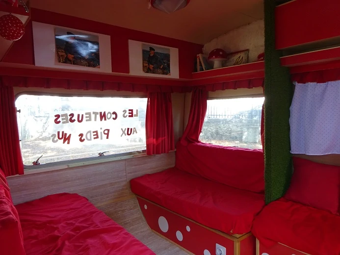 photo de l'intérieur d'une caravane décorée en rouge avec des pois blancs sur une des vitres on lit les conteuses aux pieds nus