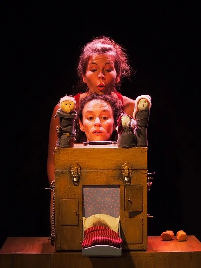 gros plan de deux comédiennes jouant leur spectacle elles regardent étonnées au dessus d'une boite avec des marionnettes
