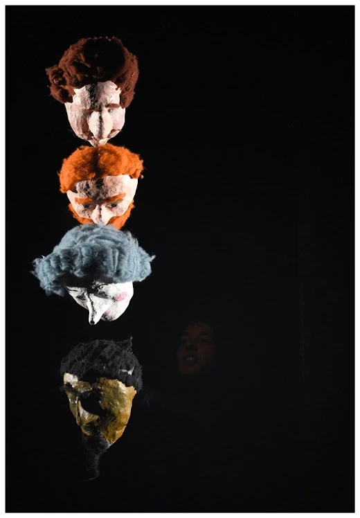 photo de spectacle dans l'ombre une comédienne manipule quatre marionnettes sous forme de têtes humaines des invités du bal de Barbe Bleue